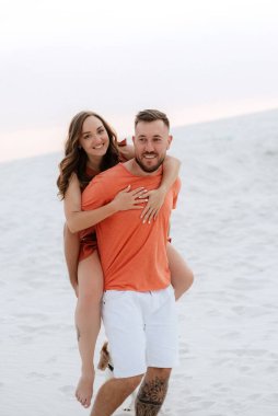 Turuncu elbiseli genç çift ve köpek çölde beyaz kumlarda