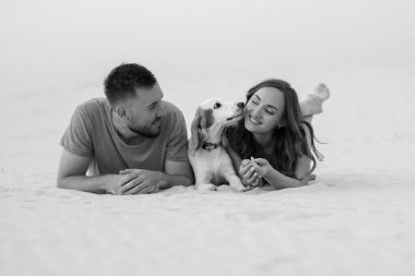 Turuncu elbiseli genç çift ve köpek çölde beyaz kumlarda