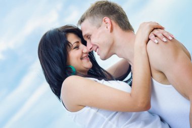 Deniz kıyısında kot pantolon ve beyaz tişörtlü bir adam ve bir kız.