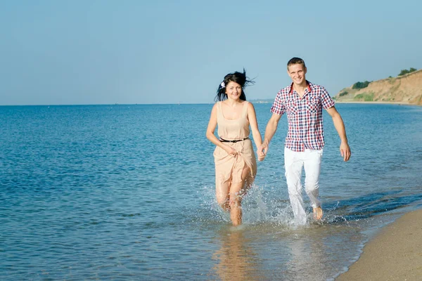 一个男的和一个女的沿着海滨散步 在水里游泳 — 图库照片