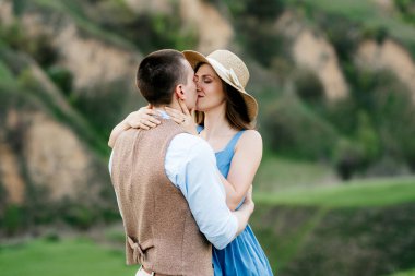 Genç çift, bir adam ve bir kız yeşil dağ tepelerinde yürüyorlar.