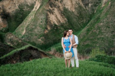 Genç çift, bir adam ve bir kız yeşil dağ tepelerinde yürüyorlar.