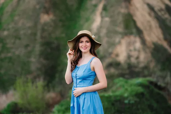 山の緑の斜面に大きなつばのある藁帽子の少女 — ストック写真