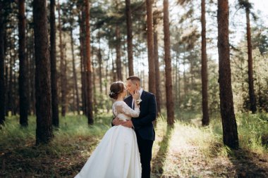 Gelin ve damat aydınlık bir günde çam ormanında yürüyorlar.