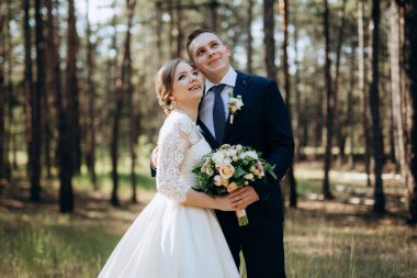 Gelin ve damat aydınlık bir günde çam ormanında yürüyorlar.