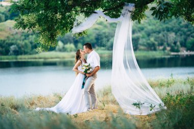 Genç bir çift, bir kız ve bir adam nehrin arka planında yürüyorlar.