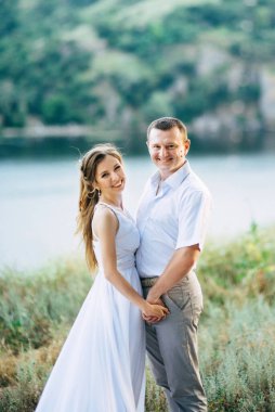 Genç bir çift, bir kız ve bir adam nehrin arka planında yürüyorlar.