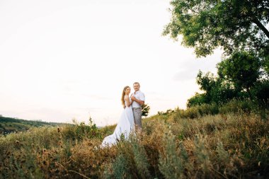 Genç bir çift, bir kız ve bir adam nehrin arka planında yürüyorlar.