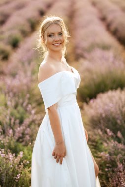 Beyaz elbiseli gelin lavanta tarlasında yürüyor.