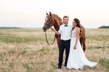 Beyaz elbiseli gelin ve kahverengi atlı beyaz gömlekli damat.