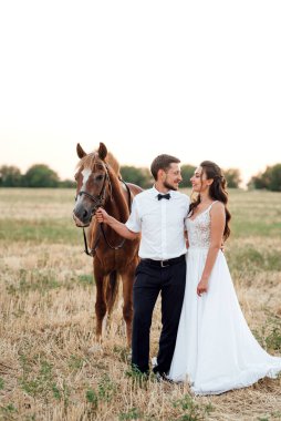 Beyaz elbiseli gelin ve kahverengi atlı beyaz gömlekli damat.