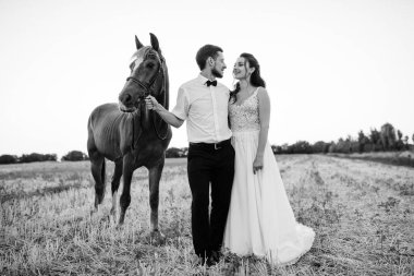 Beyaz elbiseli gelin ve kahverengi atlı beyaz gömlekli damat.