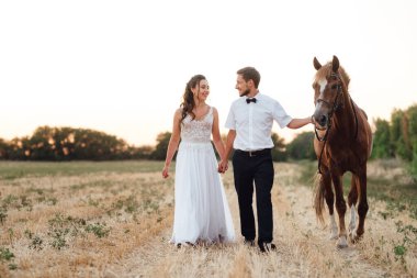 Beyaz elbiseli gelin ve kahverengi atlı beyaz gömlekli damat.
