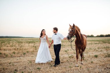 Beyaz elbiseli gelin ve kahverengi atlı beyaz gömlekli damat.