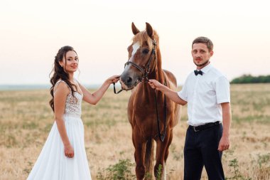 Beyaz elbiseli gelin ve kahverengi atlı beyaz gömlekli damat.