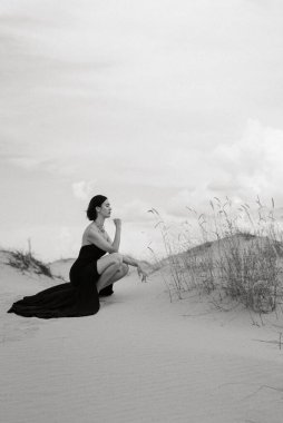 Kumlu çölde, mavi gökyüzünün altında, siyah, uzun elbiseli bir kız.