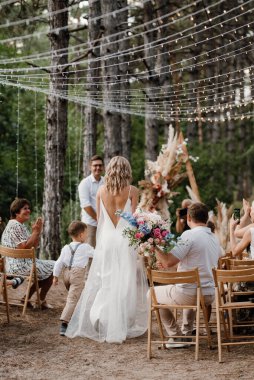 wedding ceremony of the marriage of a guy and a girl against the backdrop of an arch on a forest path