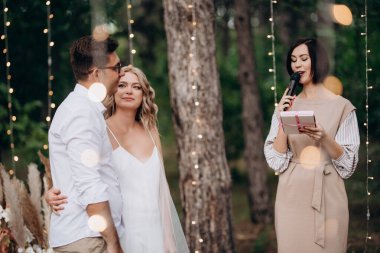 wedding ceremony of the marriage of a guy and a girl against the backdrop of an arch on a forest path