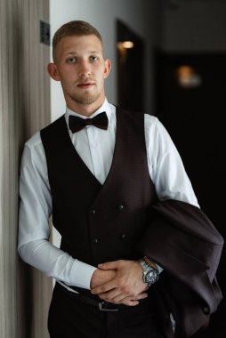 Düğün günü kahverengi takım elbiseli ve papyonlu damadın portresi.