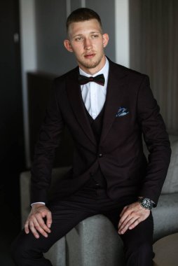 Düğün günü kahverengi takım elbiseli ve papyonlu damadın portresi.