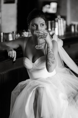 Gelin, bardaki kokteyl barına girdi. Parlak bir atmosferde, bir bardak içkiyle.