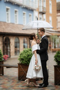 Genç çift, gelin ve damat, yağmurda yürüyen beyaz kısa elbiseli.