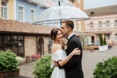 Genç çift, gelin ve damat, yağmurda yürüyen beyaz kısa elbiseli.