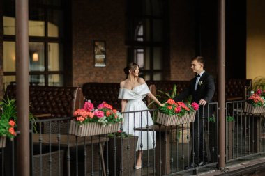 Genç çift, gelin ve damat, yağmurda yürüyen beyaz kısa elbiseli.