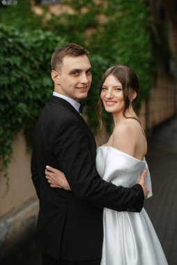 Genç çift, gelin ve damat, yağmurda yürüyen beyaz kısa elbiseli.