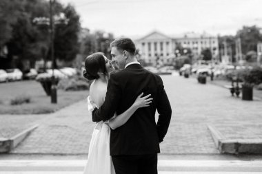 Genç çift, gelin ve damat, yağmurda yürüyen beyaz kısa elbiseli.