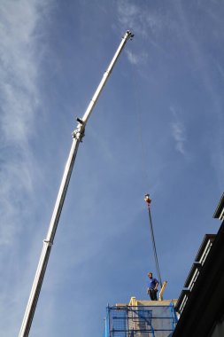 Zanaatkar, marangoz, çatı tamircisi, yüksek bir binanın çatısının tamamlanmasına hazırlanıyor.