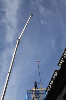 Zanaatkar, marangoz, çatı tamircisi, yüksek bir binanın çatısının tamamlanmasına hazırlanıyor.