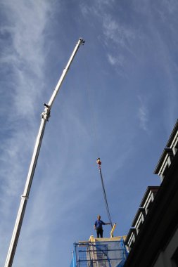 Zanaatkar, marangoz, çatı tamircisi, yüksek bir binanın çatısının tamamlanmasına hazırlanıyor.