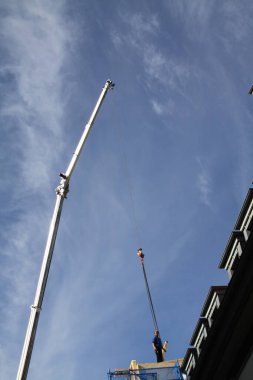 Zanaatkar, marangoz, çatı tamircisi, yüksek bir binanın çatısının tamamlanmasına hazırlanıyor.