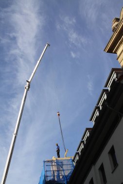 Zanaatkar, marangoz, çatı tamircisi, yüksek bir binanın çatısının tamamlanmasına hazırlanıyor.