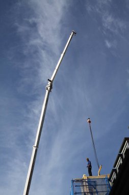 Zanaatkar, marangoz, çatı tamircisi, yüksek bir binanın çatısının tamamlanmasına hazırlanıyor.