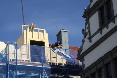 Zanaatkar, marangoz, çatı tamircisi, yüksek bir binanın çatısının tamamlanmasına hazırlanıyor.