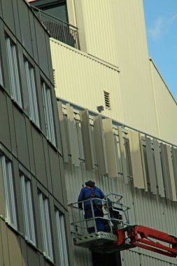 Paderborn, Kuzey Ren-Westphalia, Almanya, Ekim 28. 2020, zanaatkar platformun üzerinde duruyor ve bir cephede çalışıyor.