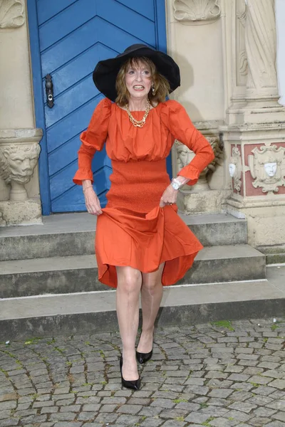 在纽豪斯城堡公园的蓝色大门前 穿着橙色晚礼服的迷人女人摆出一副迷人的姿势 — 图库照片