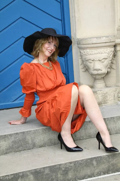Attraktive Frau Orangefarbenen Abendkleid Posiert Vor Blauer Tür Schlosspark Neuhaus lizenzfreie Stockfotos