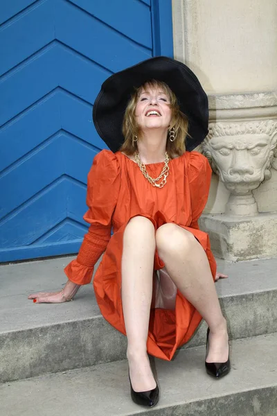Attraktive Frau Orangefarbenen Abendkleid Posiert Vor Blauer Tür Schlosspark Neuhaus lizenzfreie Stockbilder