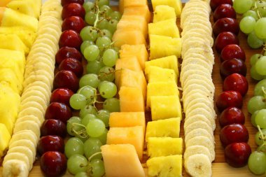 Tahta, ananas, üzüm, kiraz, muz, kavun üzerine dekoratif bir şekilde dizilmiş farklı meyve çeşitleri yakın çekim,