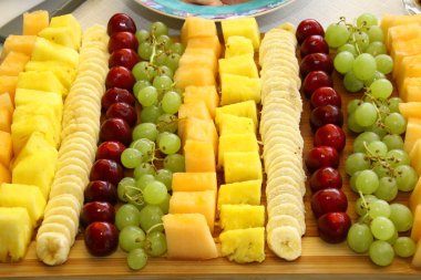 Tahta, ananas, üzüm, kiraz, muz, kavun üzerine dekoratif bir şekilde dizilmiş farklı meyve çeşitleri yakın çekim,