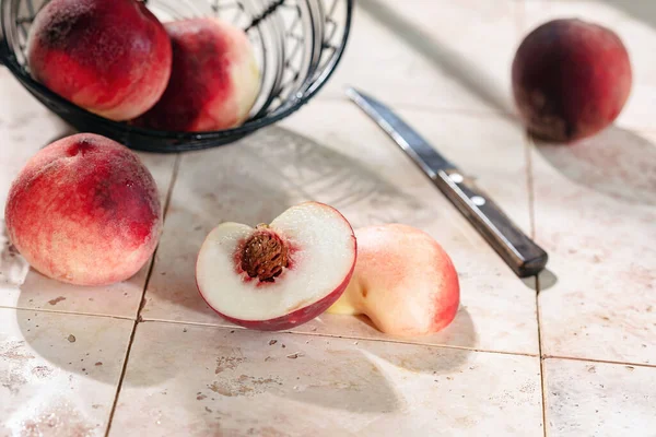 Peaches on a tile table, cut into pieces, knife