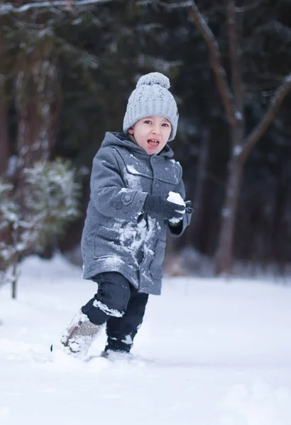 Ragazzo in cappotto e cappello giocare palle di neve fuori — Foto Stock