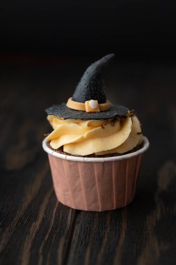 Siyah arka planda cadı şapkası şeklinde bir kek. Cadılar Bayramı konsepti. 