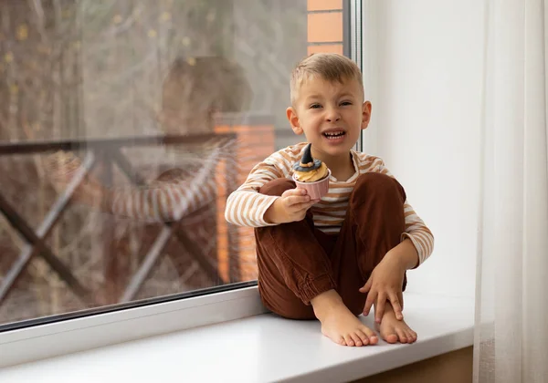 Little Boy Sits Windowsill Eats Cupcake Form Witch Hat Halloween — Stock Photo, Image