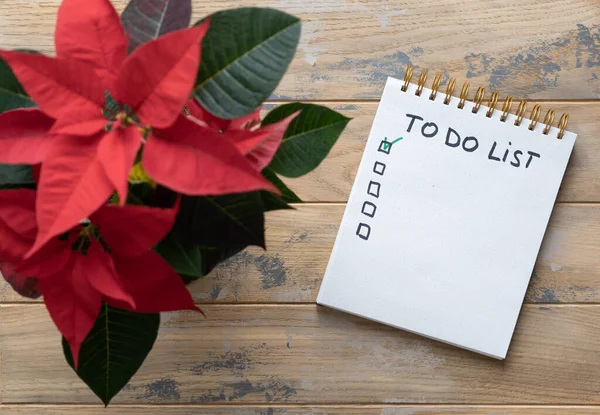 Notepad on the wooden background with the inscription - To do list. Poinsettia in the pot.