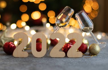 2022 numaralı ahşap, iki bardak şampanya ve çelenk ışıklarını söndürün.