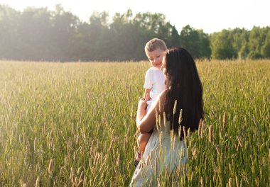 Anne oğlunu kollarına alıp kucaklıyor. Mutlu aile ve ebeveyn sevgisi kavramı. 
